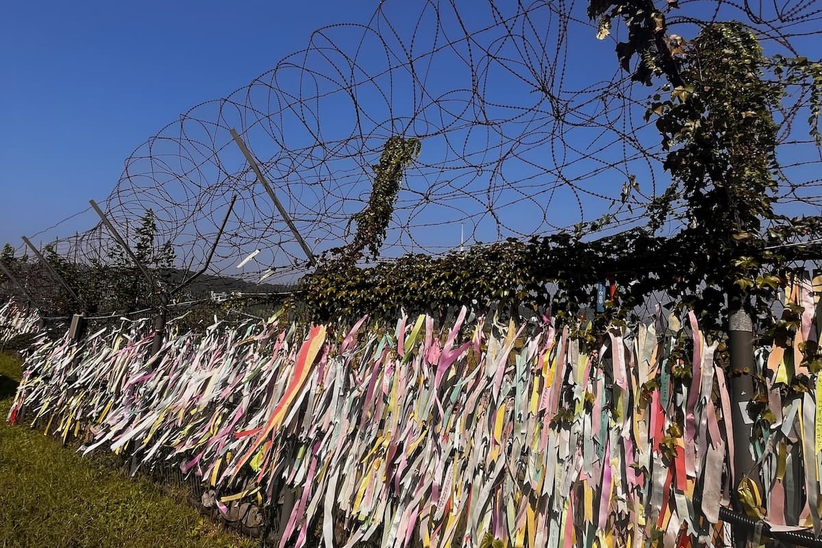 Ribbons with messages tied to barbed wire fence at border of Korea