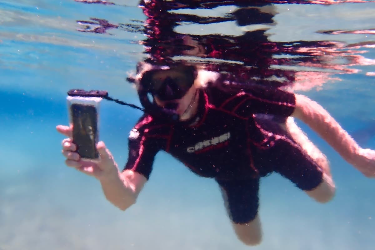 Man snorkelling holding an iPhone underwater
