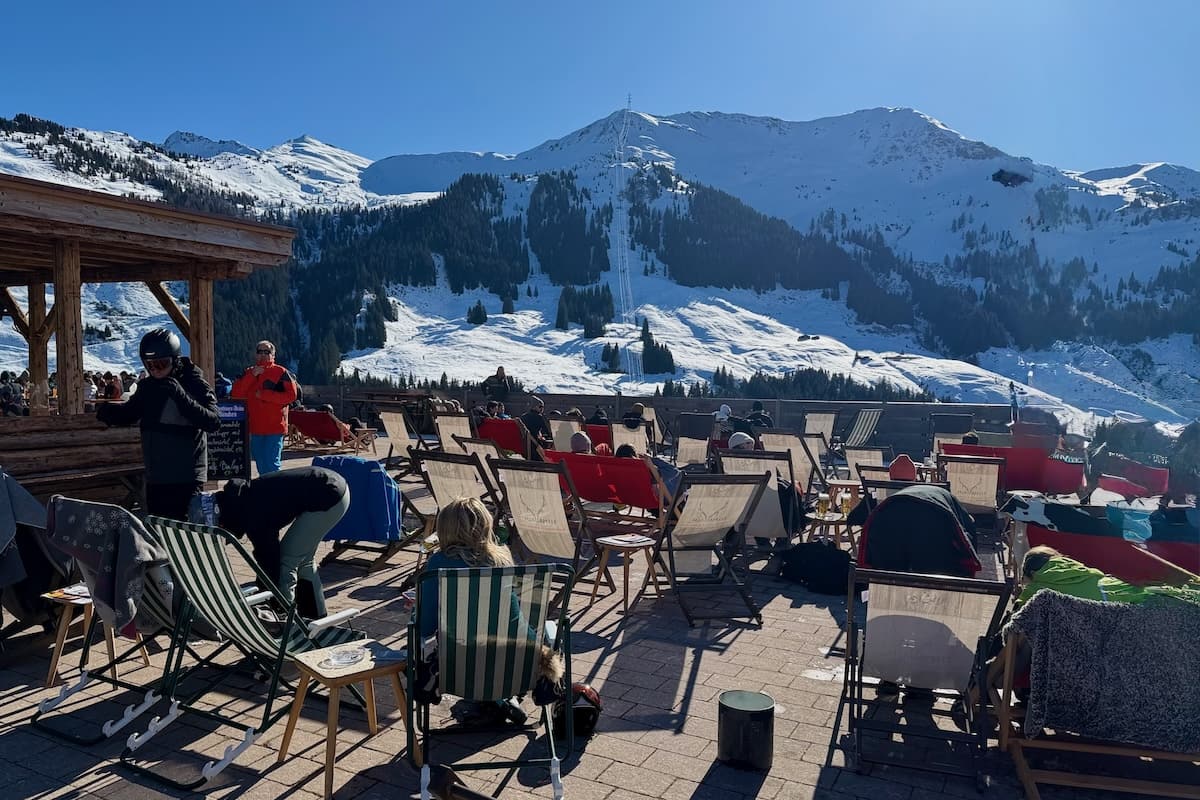 Sunny terrace of deckchairs at Ellmaualm looking at snowy mountain in Saalbach-Hinterglemm, Austria