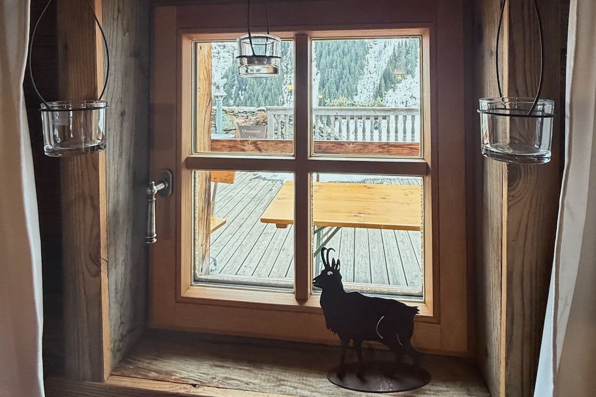 View of trees and mountain through window of Ossmanalm in Saalbach-Hinterglemm, Austria