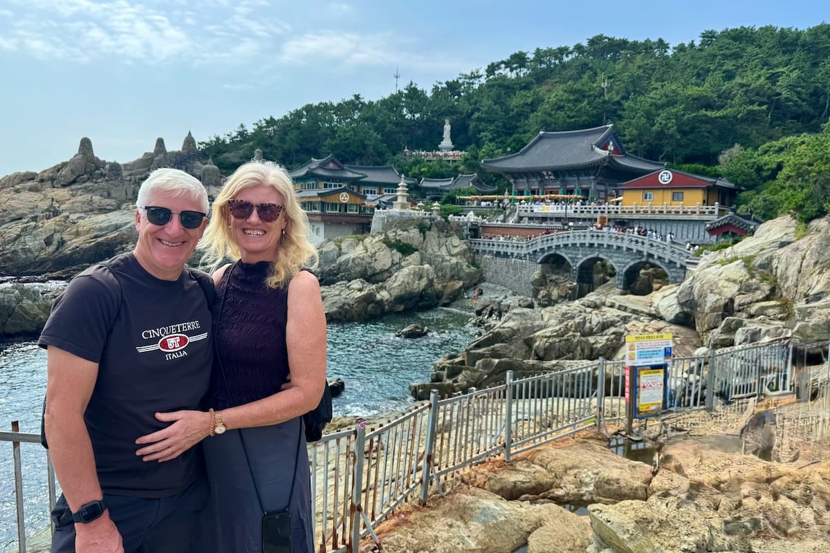 Smiling couple and view of rocky coast of Haedong Yongung Temple Busan Korea