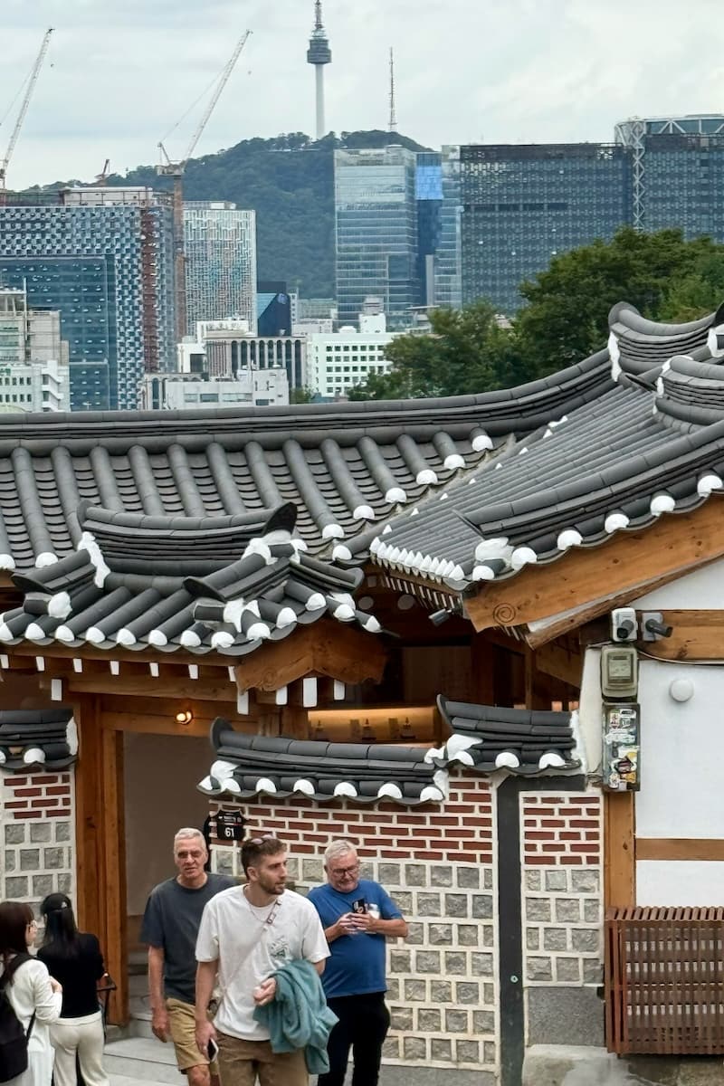 Tiled roofs of Bukchon Hanock Village with Seoul skyscrapers inn the background
