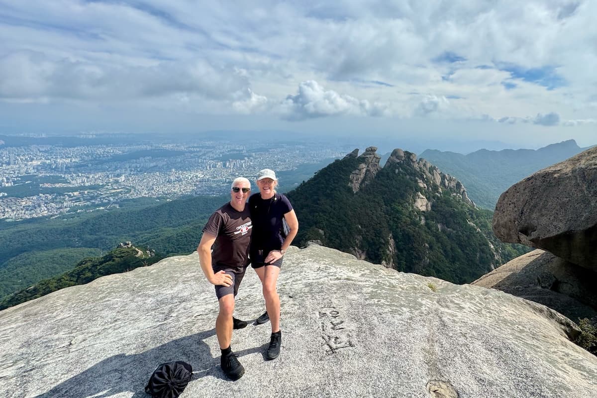 Couple at Bukhansan Peak with panorama views of Seoul Korea in distance