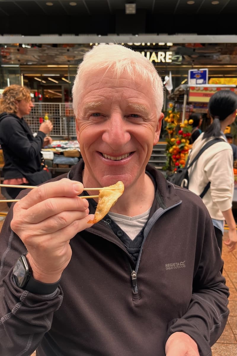 Man eating Korean street food at Myeongdong street food market in Seoul
