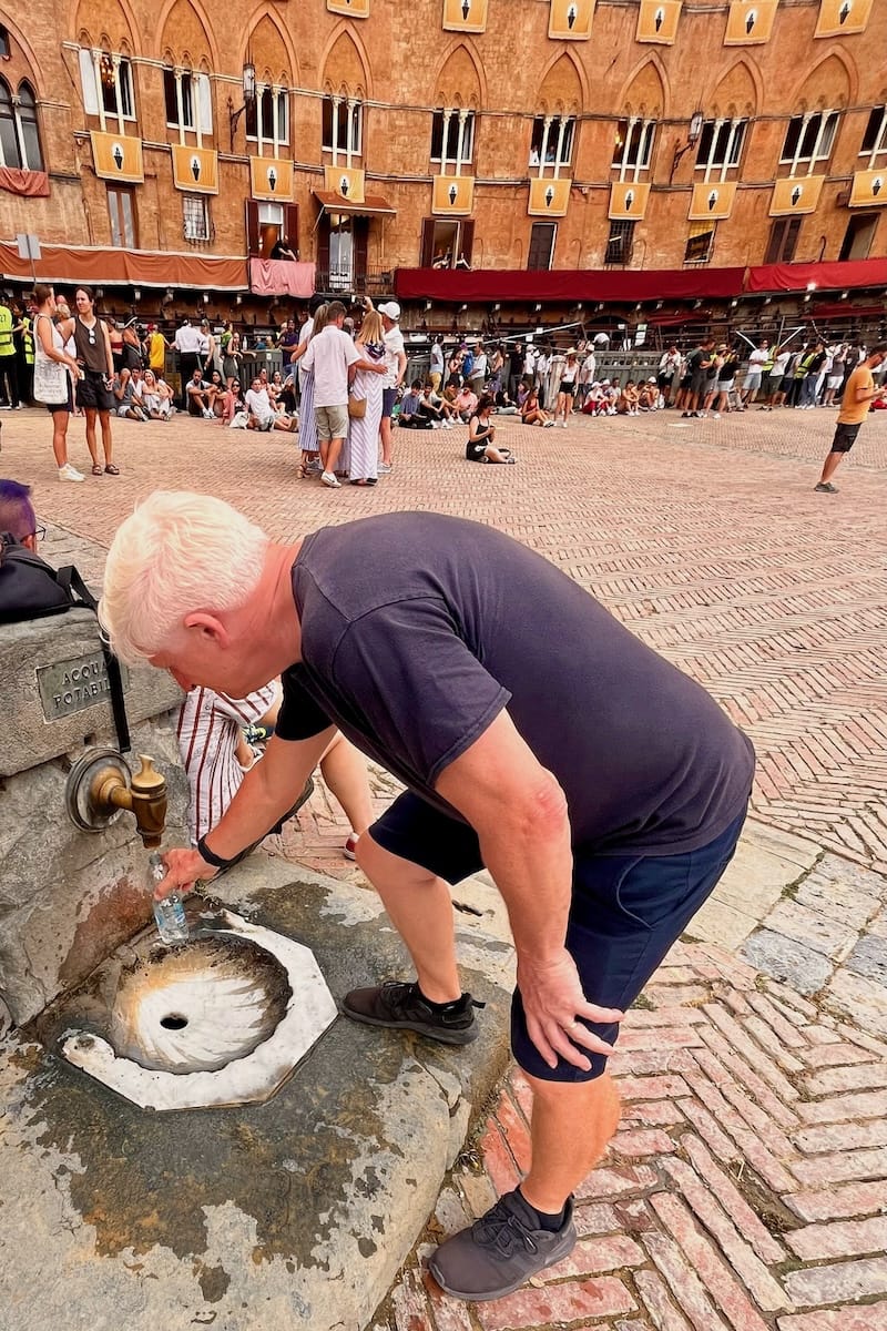 Collecting drinking water from tap in Piazza del Campo at Palio di Siena