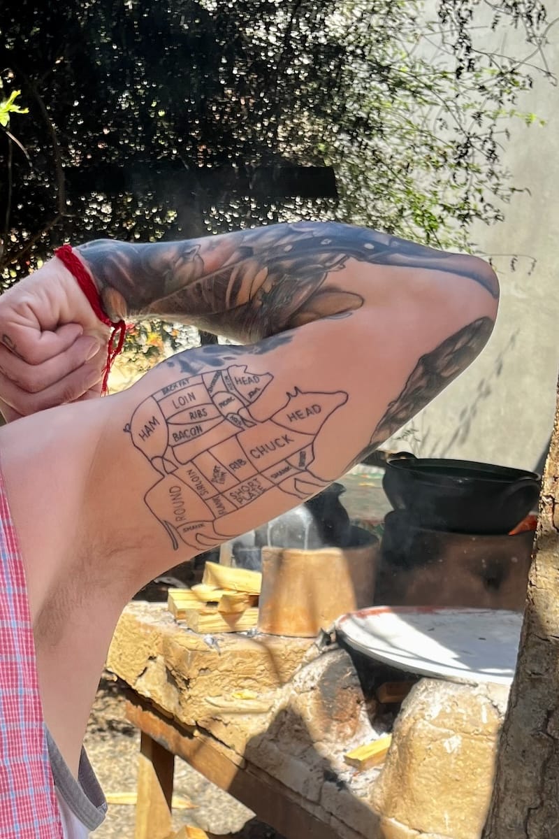 Tattoos of meat cuts on man's bicep